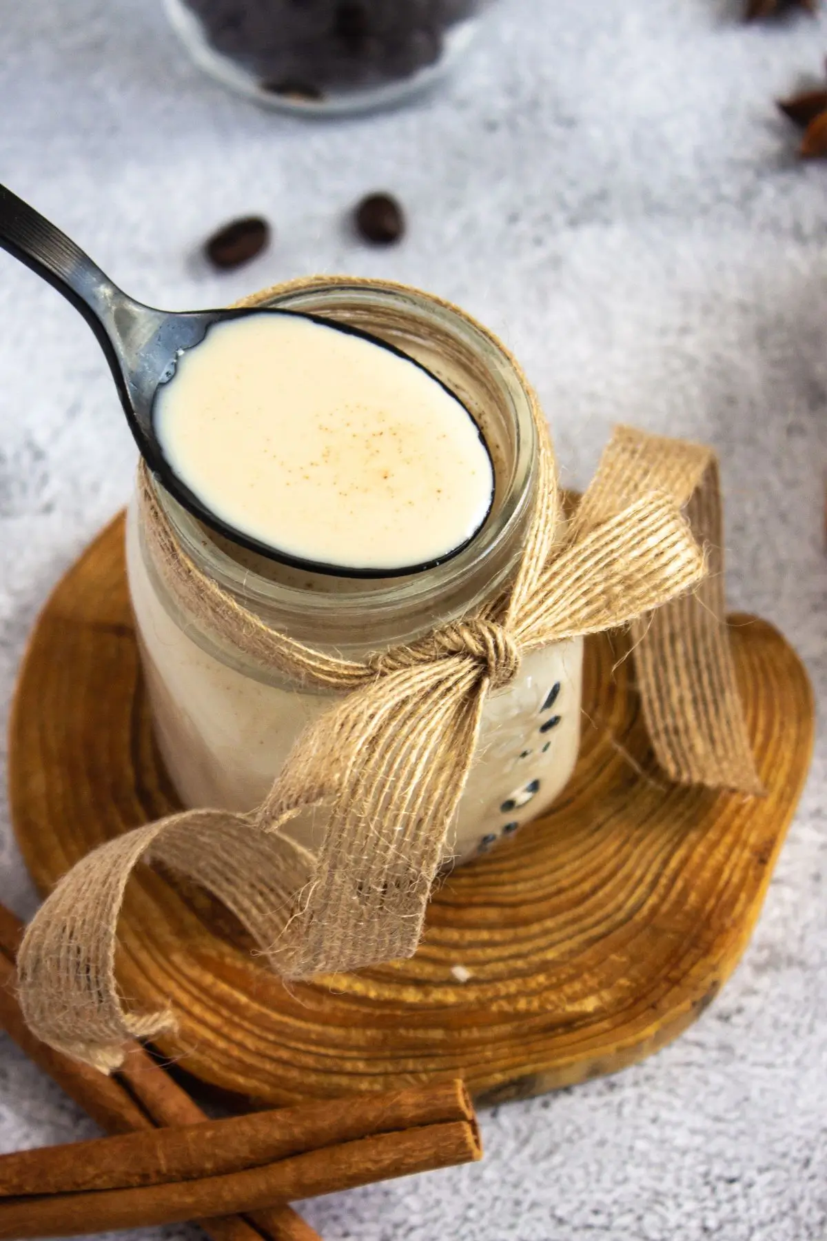 Homemade Cinnamon Vanilla Creamer (Cinnabon-Style) Rustic jar of DIY coffee whitener tied with burlap ribbon on a wood slice