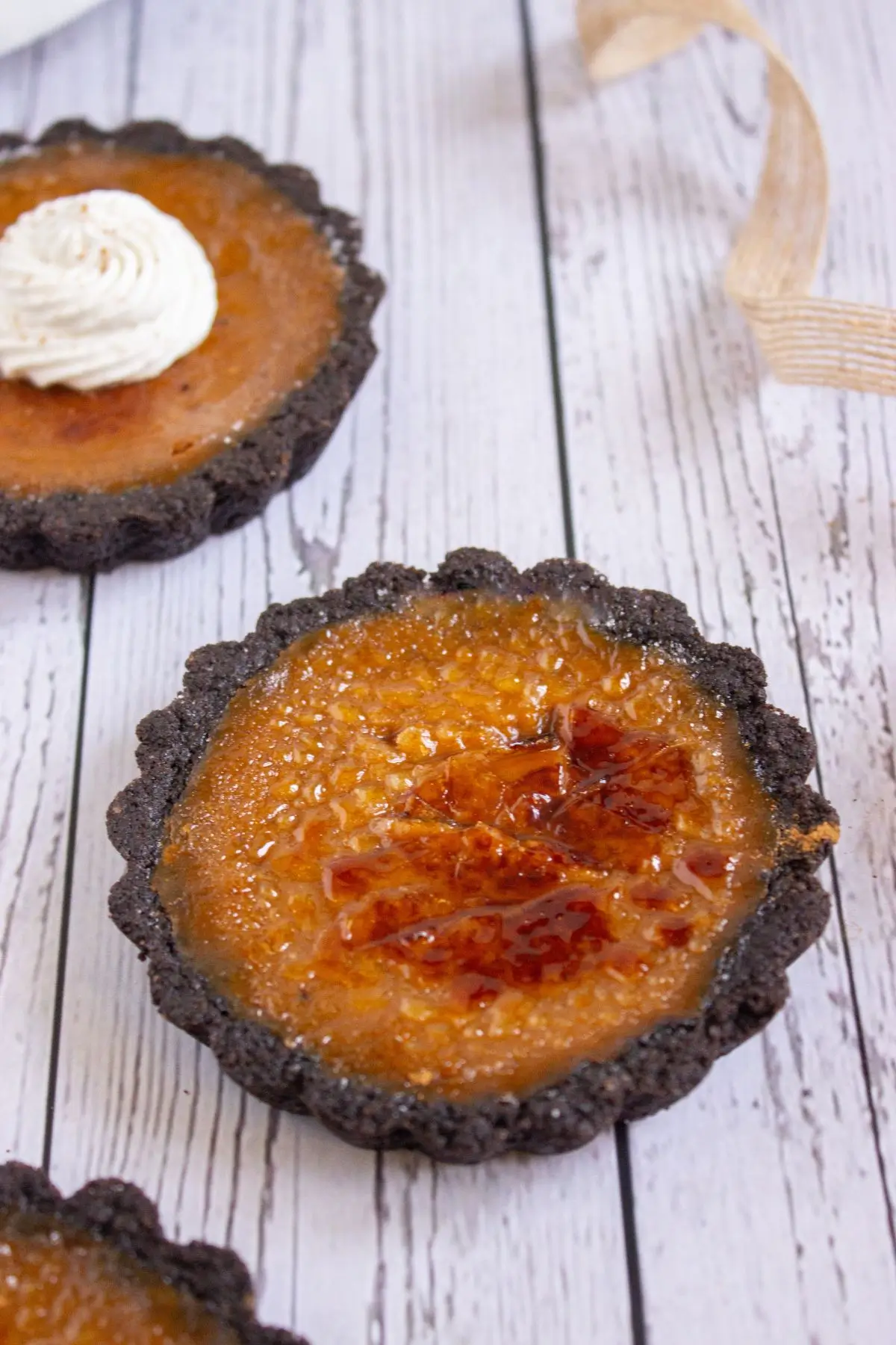 Close-up of pumpkin mini tart with caramelized sugar topping and chocolate crust, a rich and creamy pumpkin tartlet dessert.