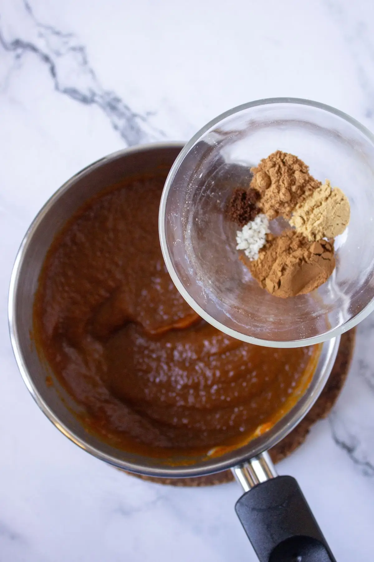 Adding fall spices like cinnamon, nutmeg, and ginger into pumpkin puree for the perfect pumpkin tart recipe filling.