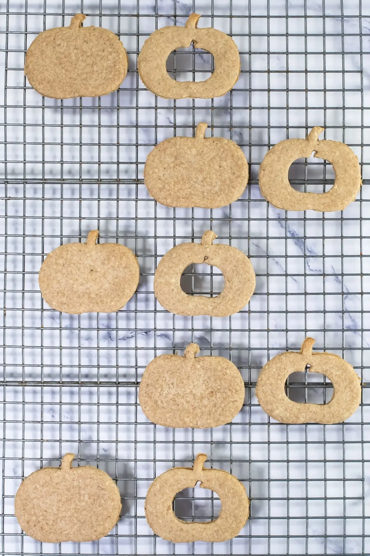The Bestest Pumpkin Linzer Cookies Pumpkin-shaped cutout cookies cooling on a wire rack