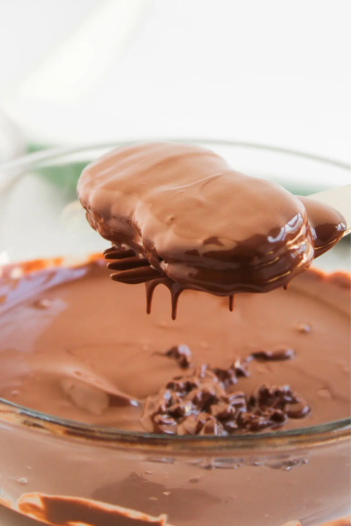 Reindeer Nutter Butter Cookies Fork lifting chocolate-coated candy over a bowl of melted chocolate