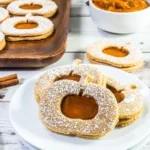 Pumpkin-shaped linzer cookies with pumpkin butter filling, dusted sugar