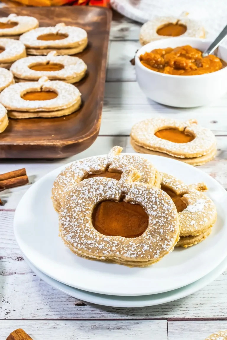 Pumpkin-shaped linzer cookies with pumpkin butter filling, dusted sugar