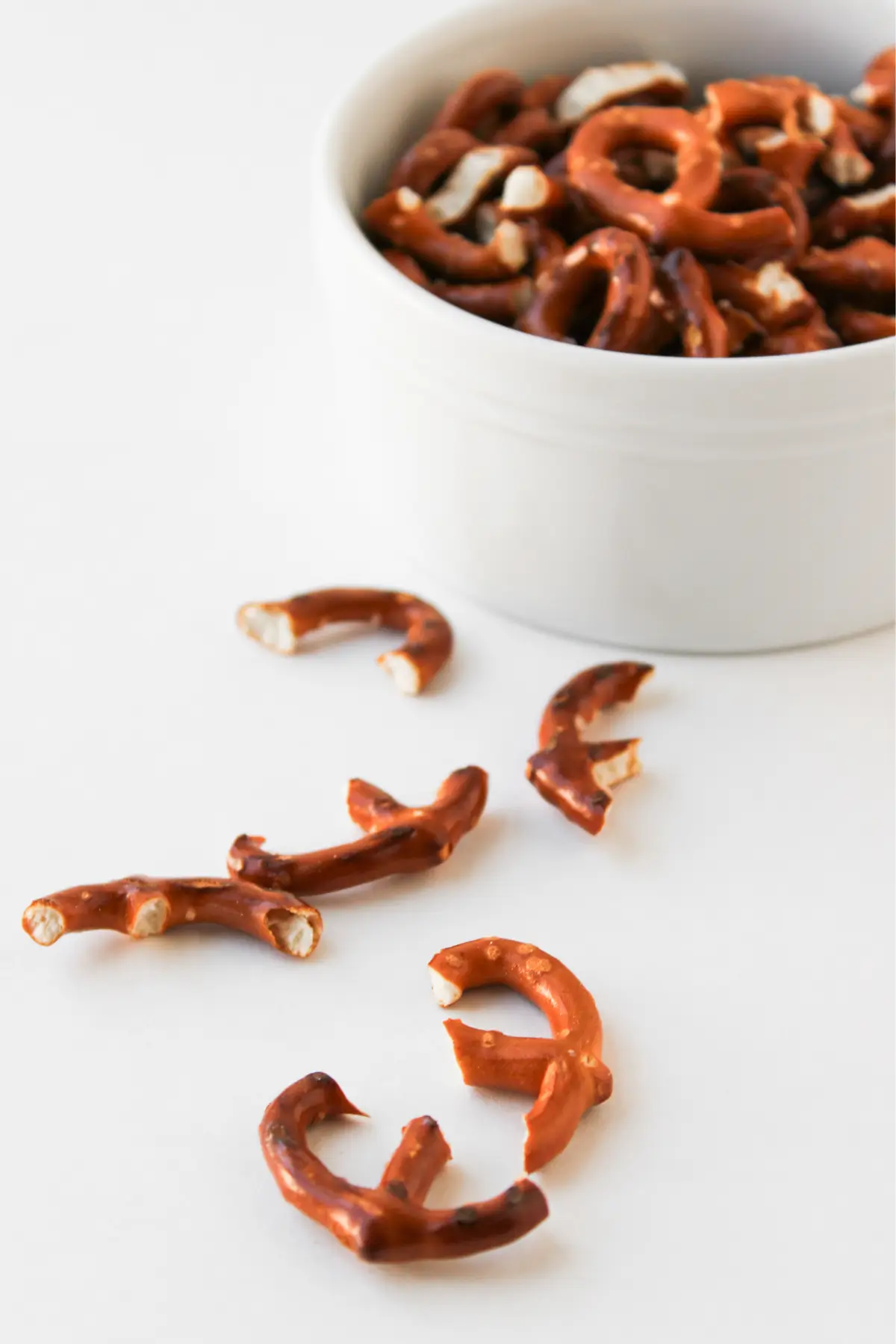 Reindeer Nutter Butter Cookies Broken salted pretzel pieces with a white bowl of mini pretzels on white surface