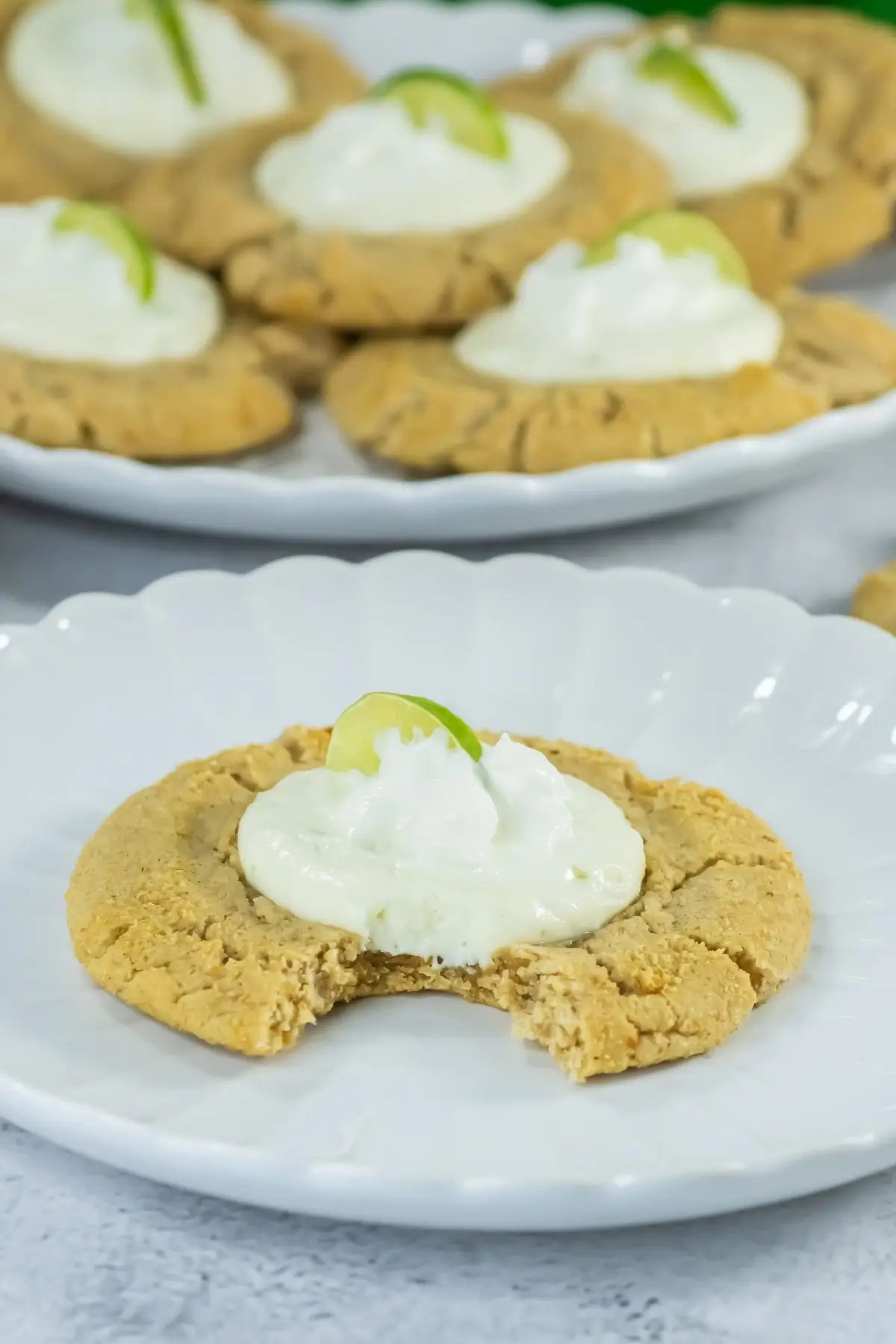 Key Lime Pie Cookies Inspired by Crumble Key lime cheesecake cookie with cream topping, bite taken on white plate