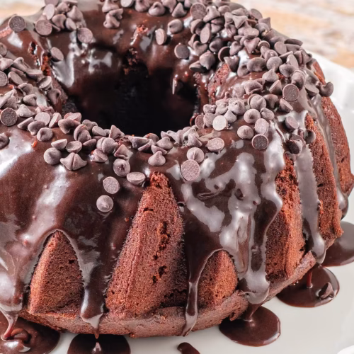 Homemade sour cream bundt cake with deep chocolate flavor, glossy glaze, and extra chocolate chips on top