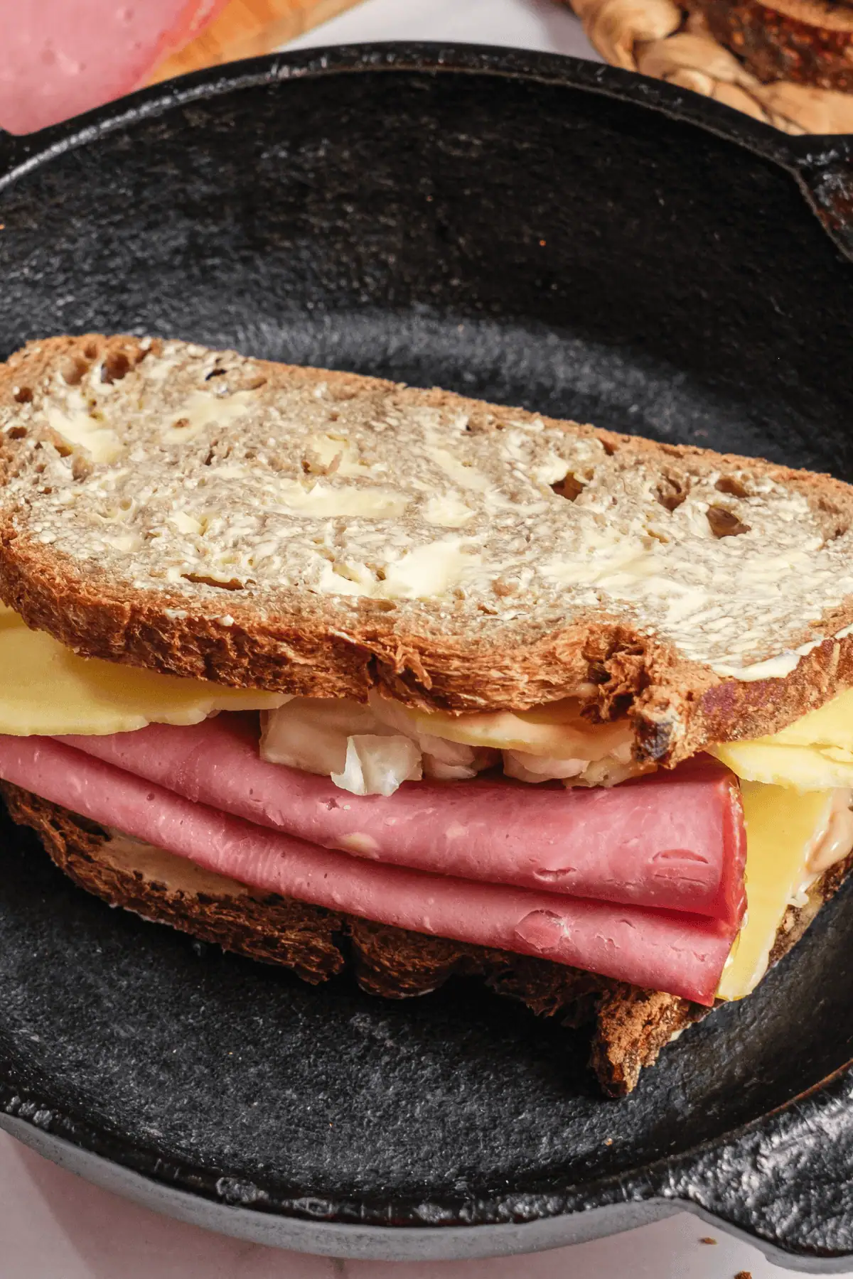 Butter-toasted Reuben sandwich with corned beef, Swiss, and sauerkraut on rye in cast-iron skillet
