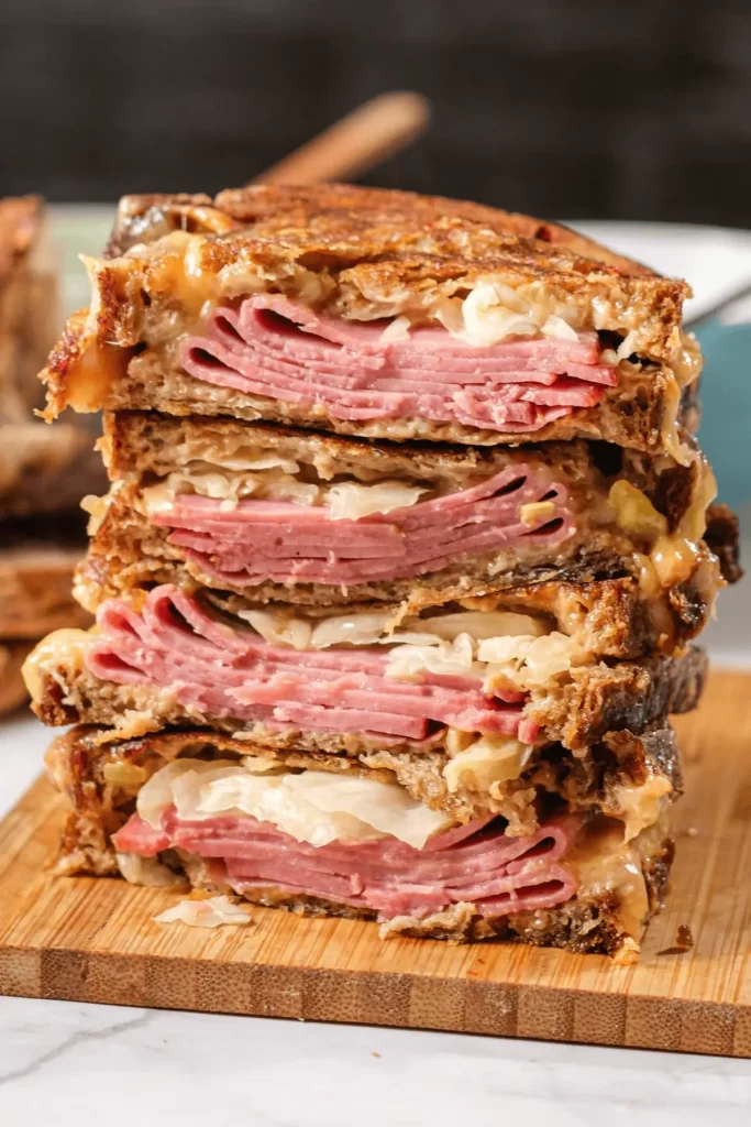 Close-up of stacked Reuben sandwich with corned beef, sauerkraut, and melted Swiss on rye