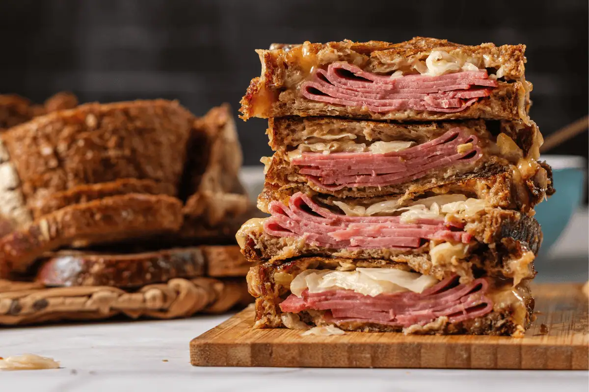 Stacked Reuben sandwich with corned beef, Swiss cheese, and sauerkraut on grilled rye