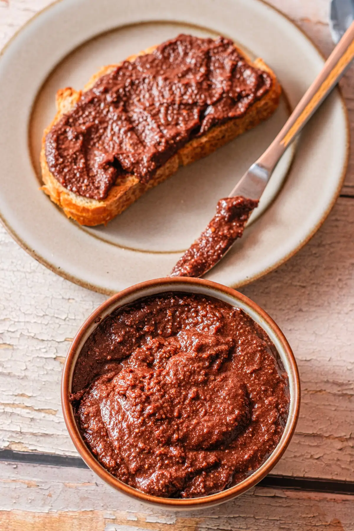 Homemade chocolate hazelnut spread on toast, with bowl and knife on plate