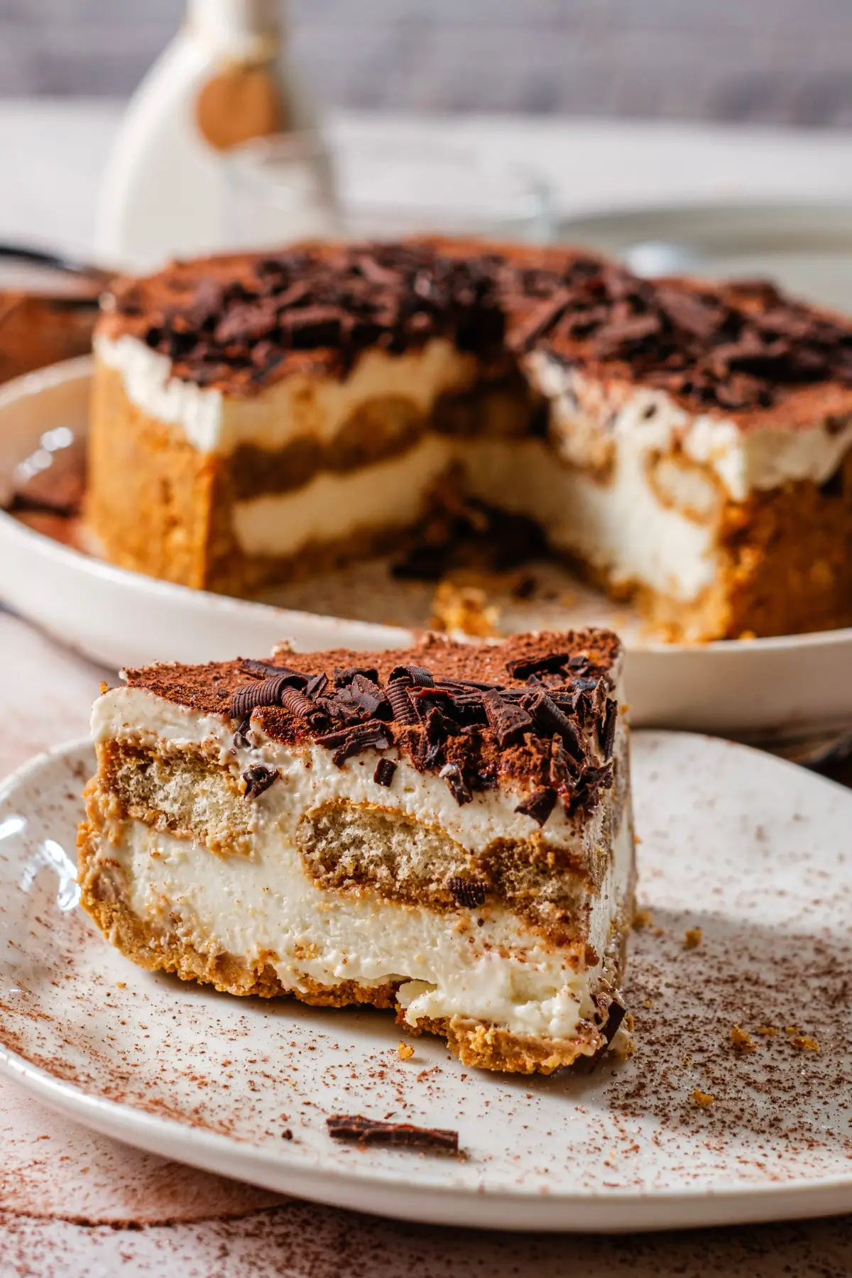 Slice of classic tiramisu with mascarpone layers, cocoa powder, and chocolate shavings on a plate