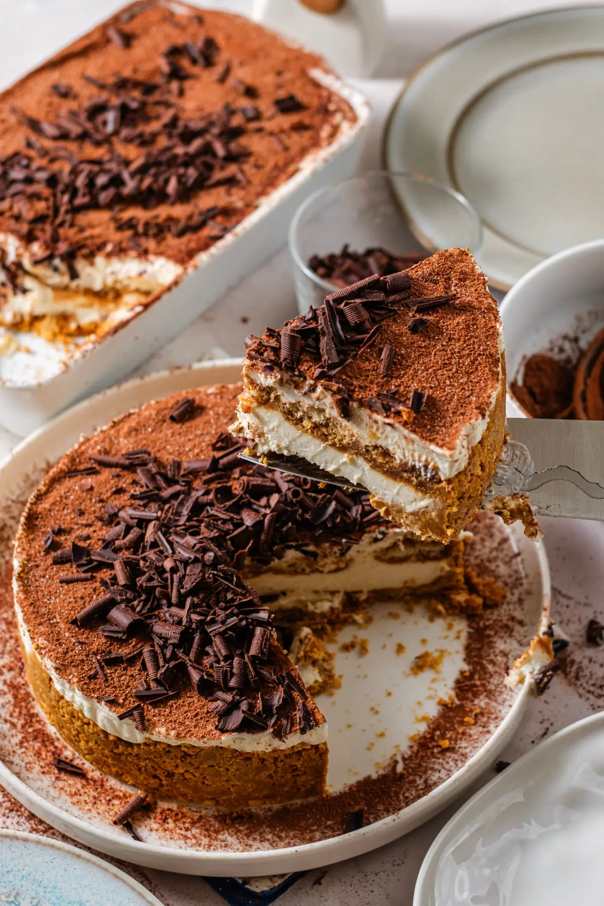 No bake, no eggs tiramisu cheesecake with cocoa and chocolate shavings, slice lifted on server