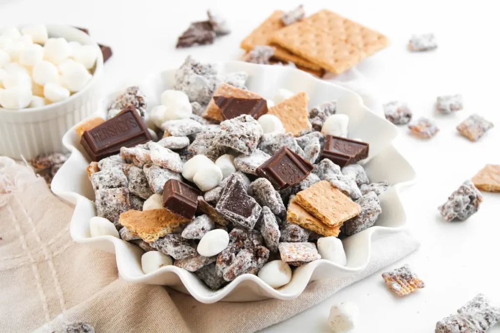 S’mores Muddy Buddies Recipe (S’mores Puppy Chow) Bowl of s'mores muddy buddies with Chex, mini marshmallows, graham crackers, and chocolate