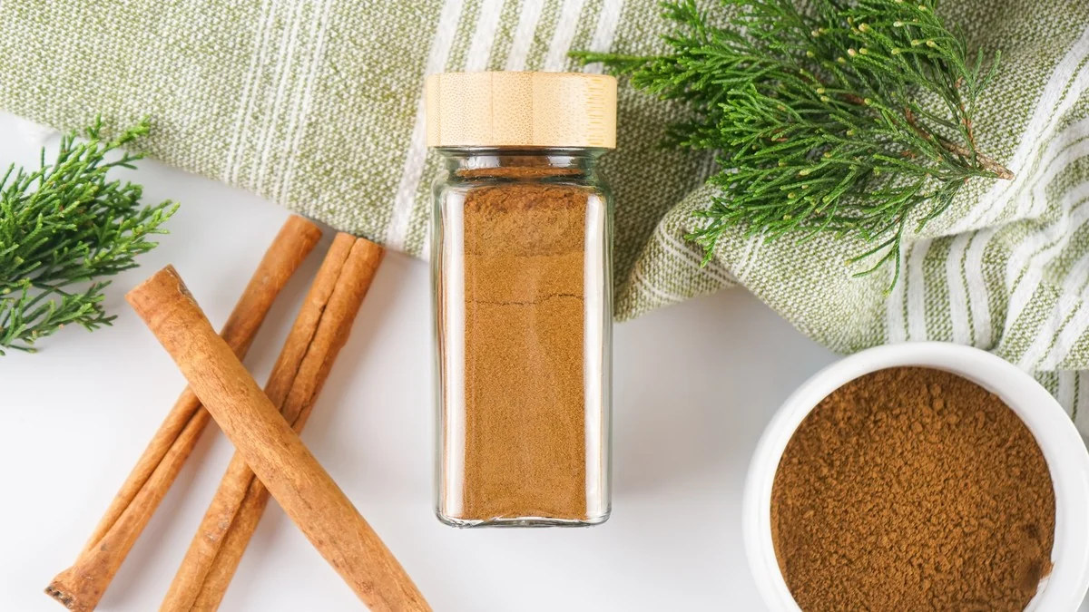 Allspice substitute in a spice jar with cinnamon sticks and a bowl of spice blend.