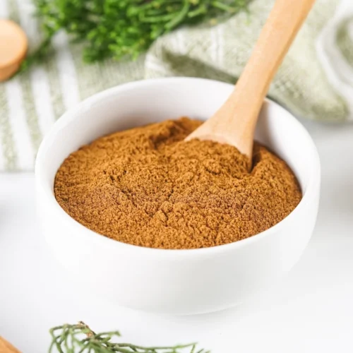 Homemade allspice substitute in a white bowl with a wooden spoon.