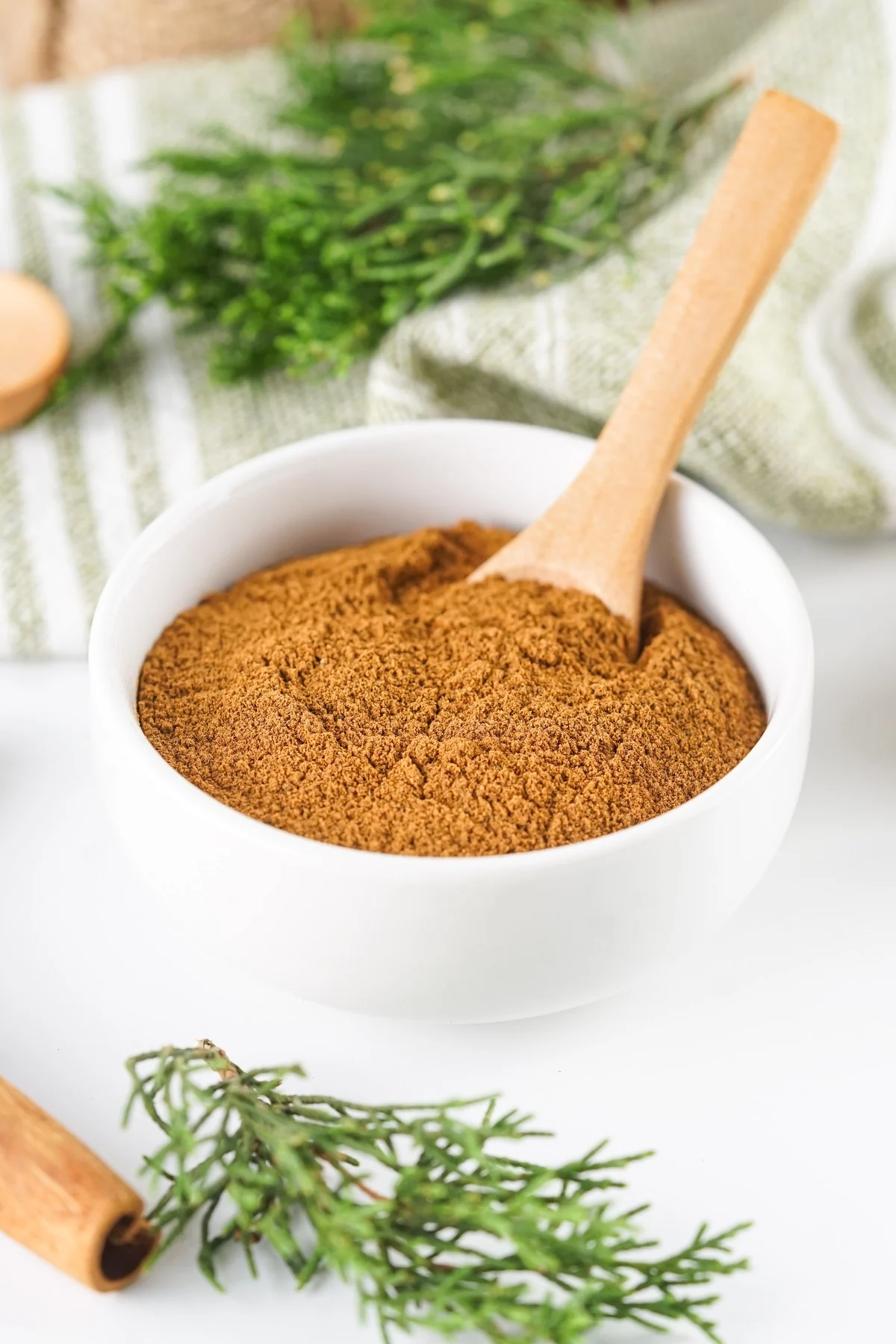 Homemade allspice substitute in a white bowl with a wooden spoon.