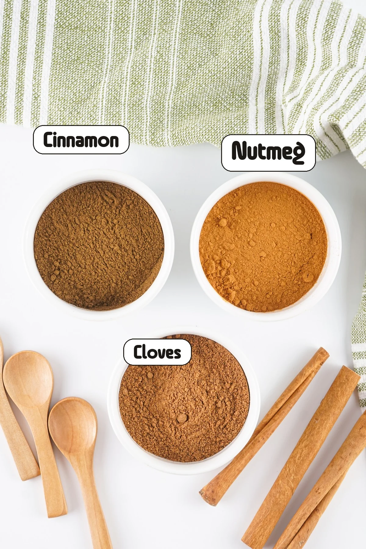 Labeled bowls of cinnamon, nutmeg, and cloves for an allspice substitute.