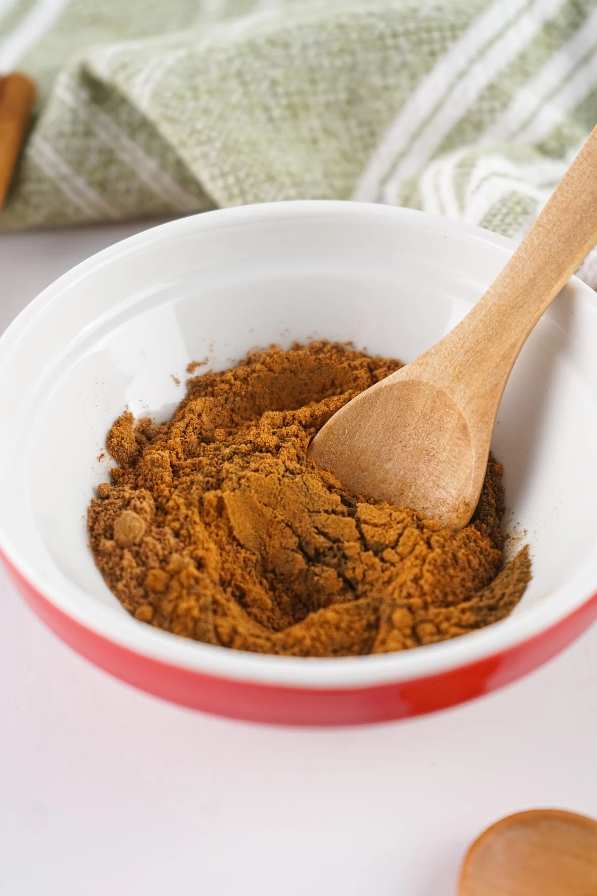 A wooden spoon stirring the homemade allspice substitute in a bowl.