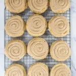Baked churro cookies topped with cinnamon frosting on a cooling rack