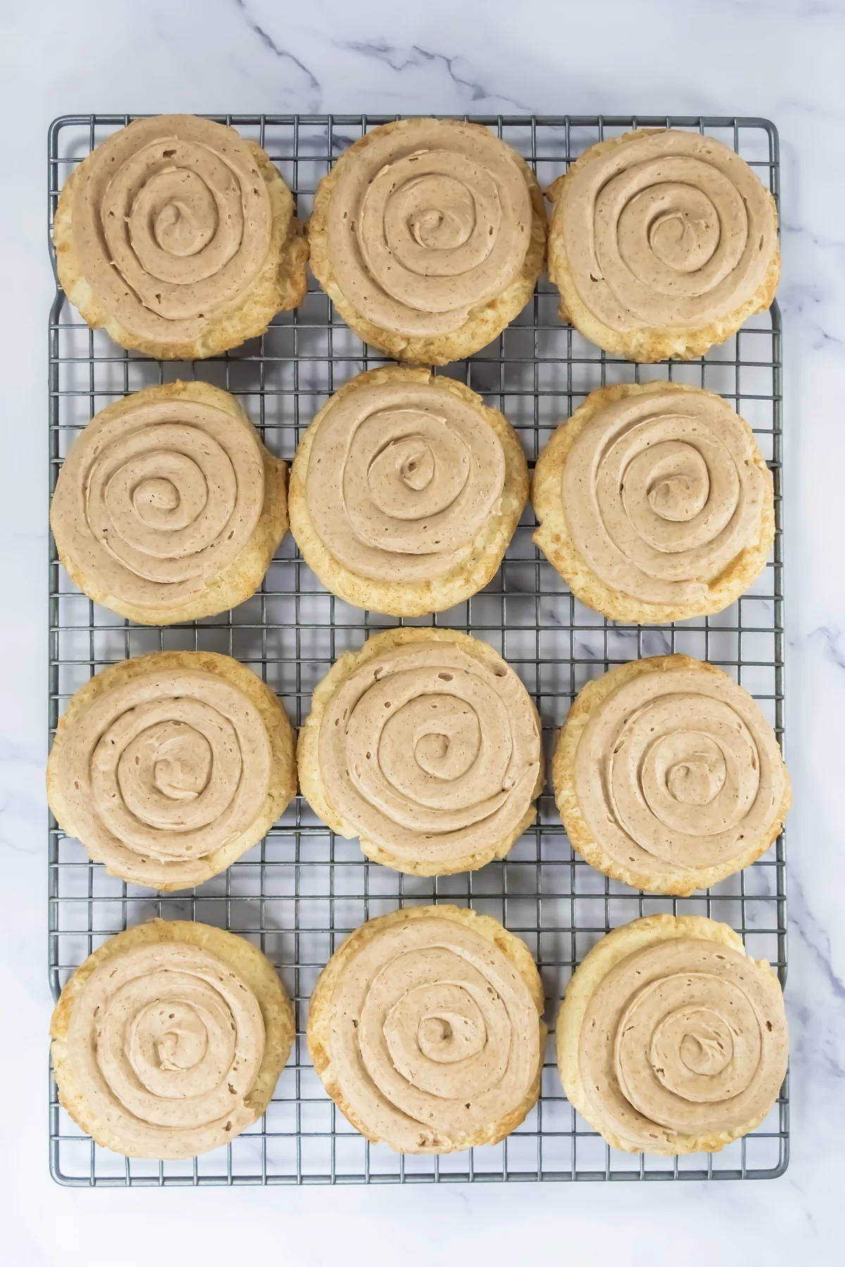 Baked churro cookies topped with cinnamon frosting on a cooling rack
