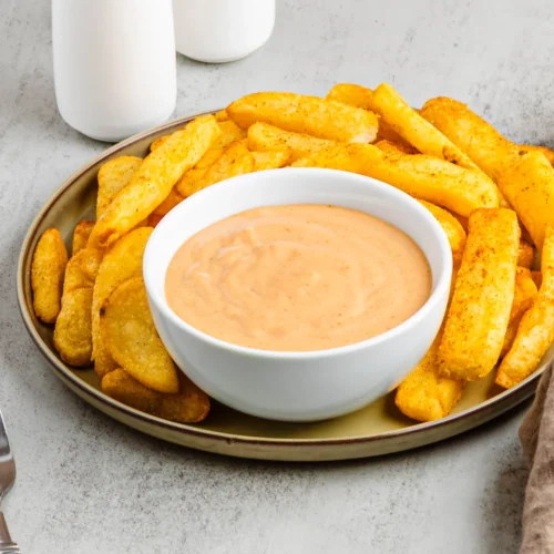 Copycat Red Robin campfire sauce in a white bowl surrounded by seasoned fries.