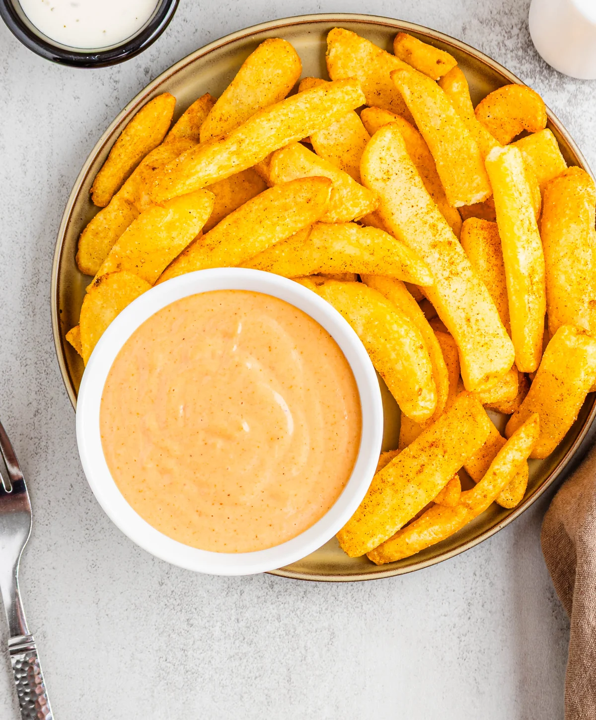 Overhead view of campfire sauce in a white bowl with seasoned fries.