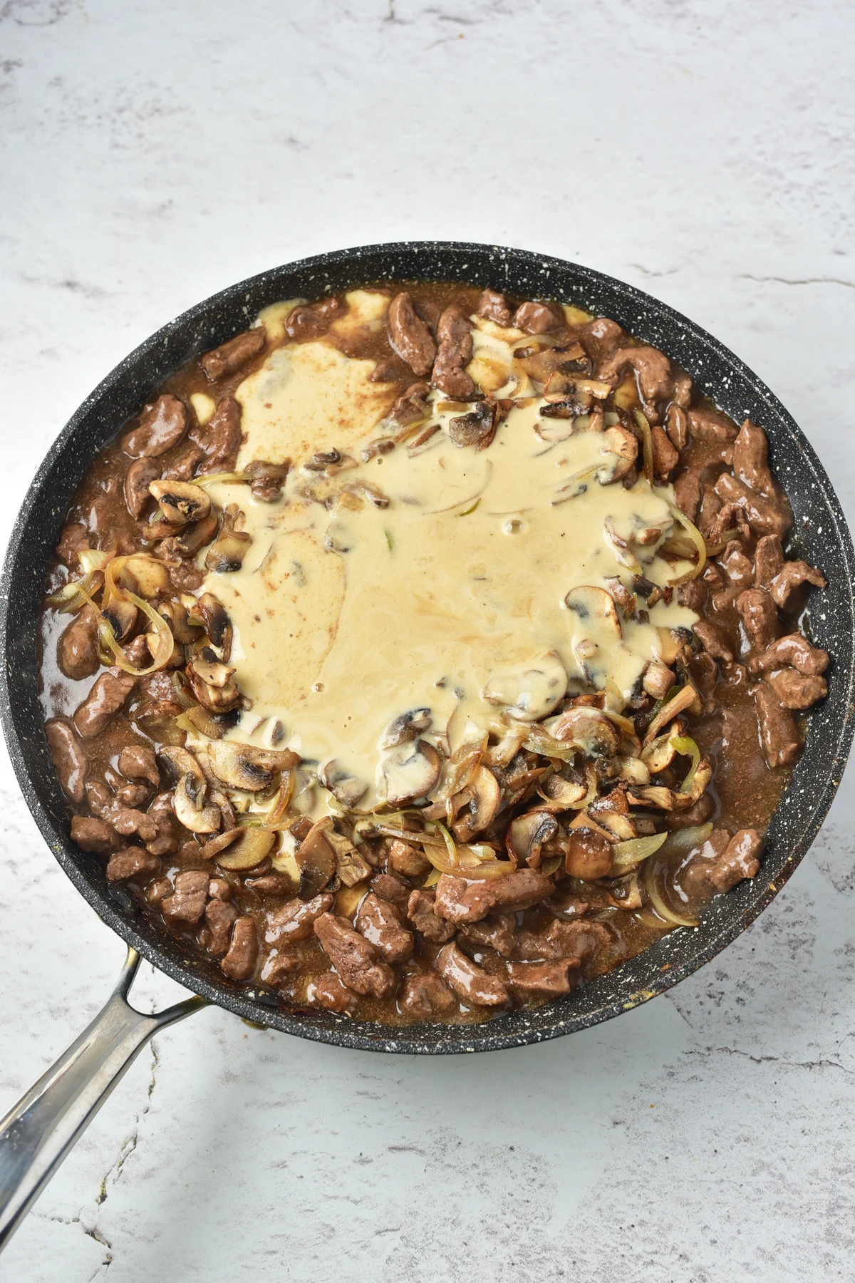 Sour cream mixture added to venison and mushrooms in a skillet