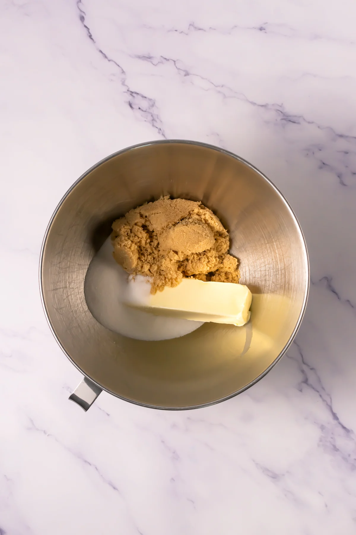 Butter, brown sugar, and granulated sugar in a metal mixing bowl.