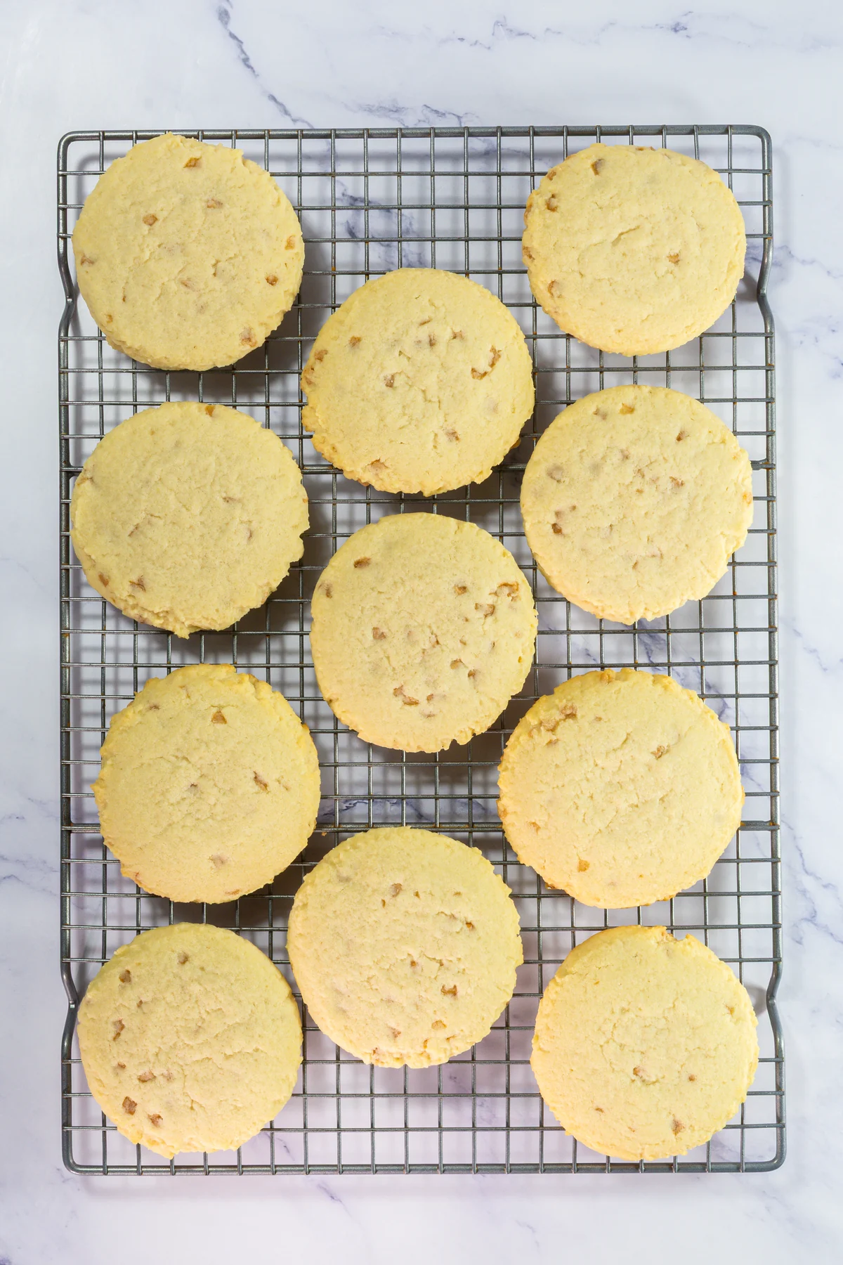 Crumbl Copycat Twix Cookies With Caramel and Toffee Large baked toffee cookies cooling on a wire rack before topping.