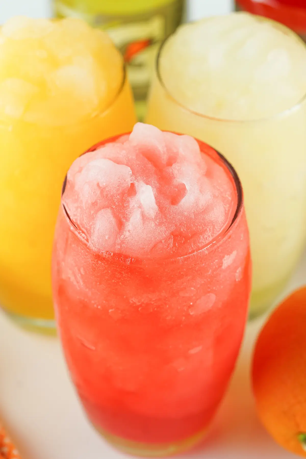 Colorful frozen fruit slushies in glasses, red, yellow and white, refreshing summer drinks