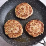 Ground chicken burger patties browned in a skillet