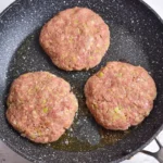 Raw ground chicken patties in a skillet before cooking
