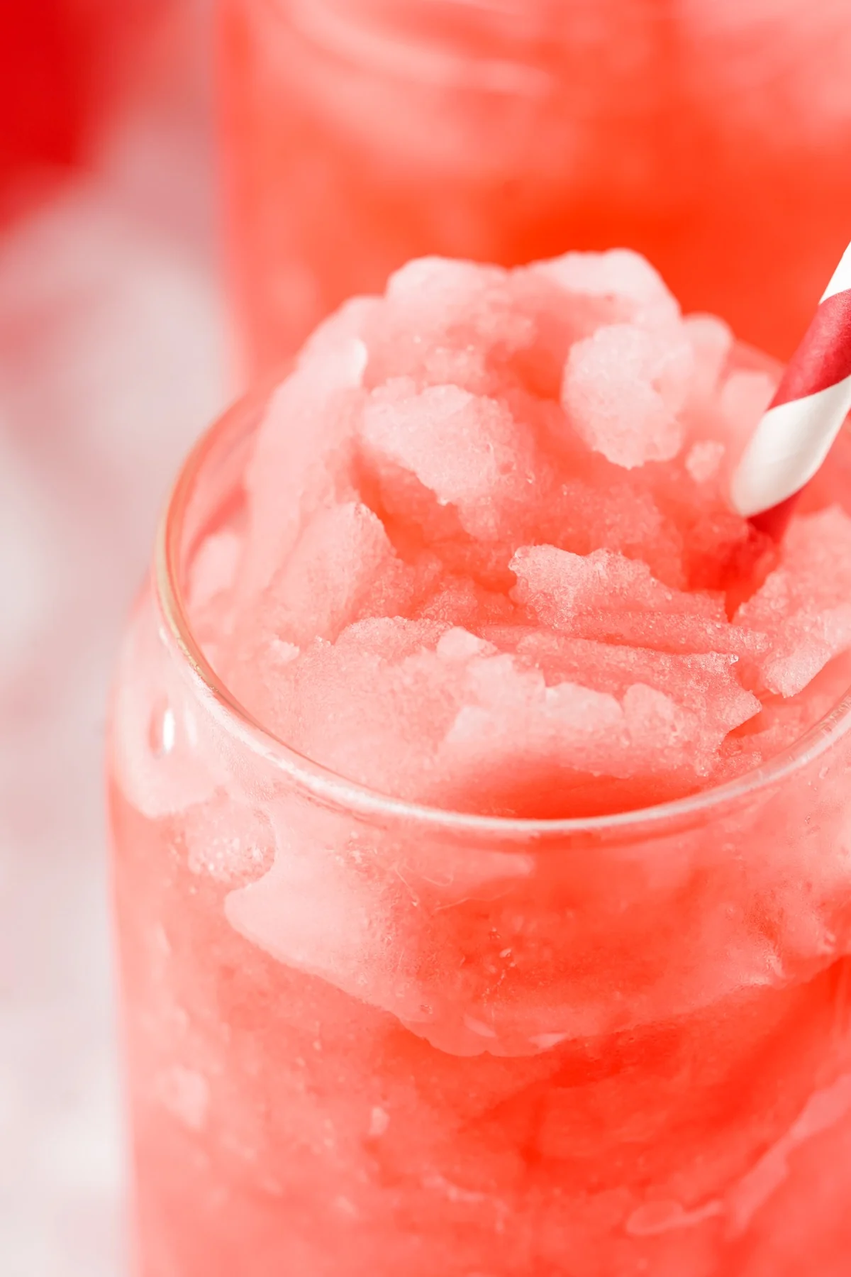Closeup of an icy red Hawaiian Punch slushie with a striped straw.