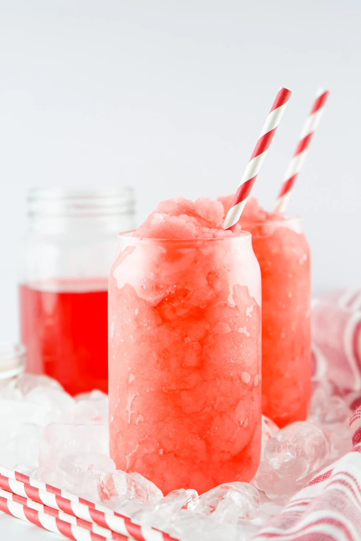 Two Hawaiian Punch slushies in glasses with striped straws and ice.