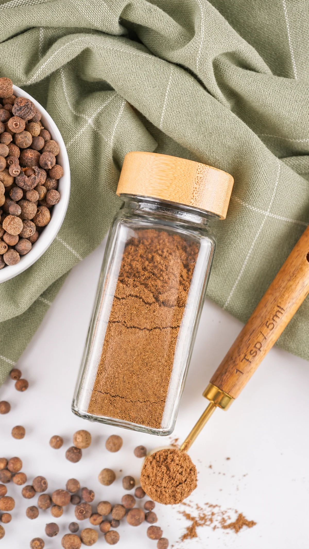 How to Make Ground Allspice From Whole Berries Freshly ground allspice stored in a glass spice jar.