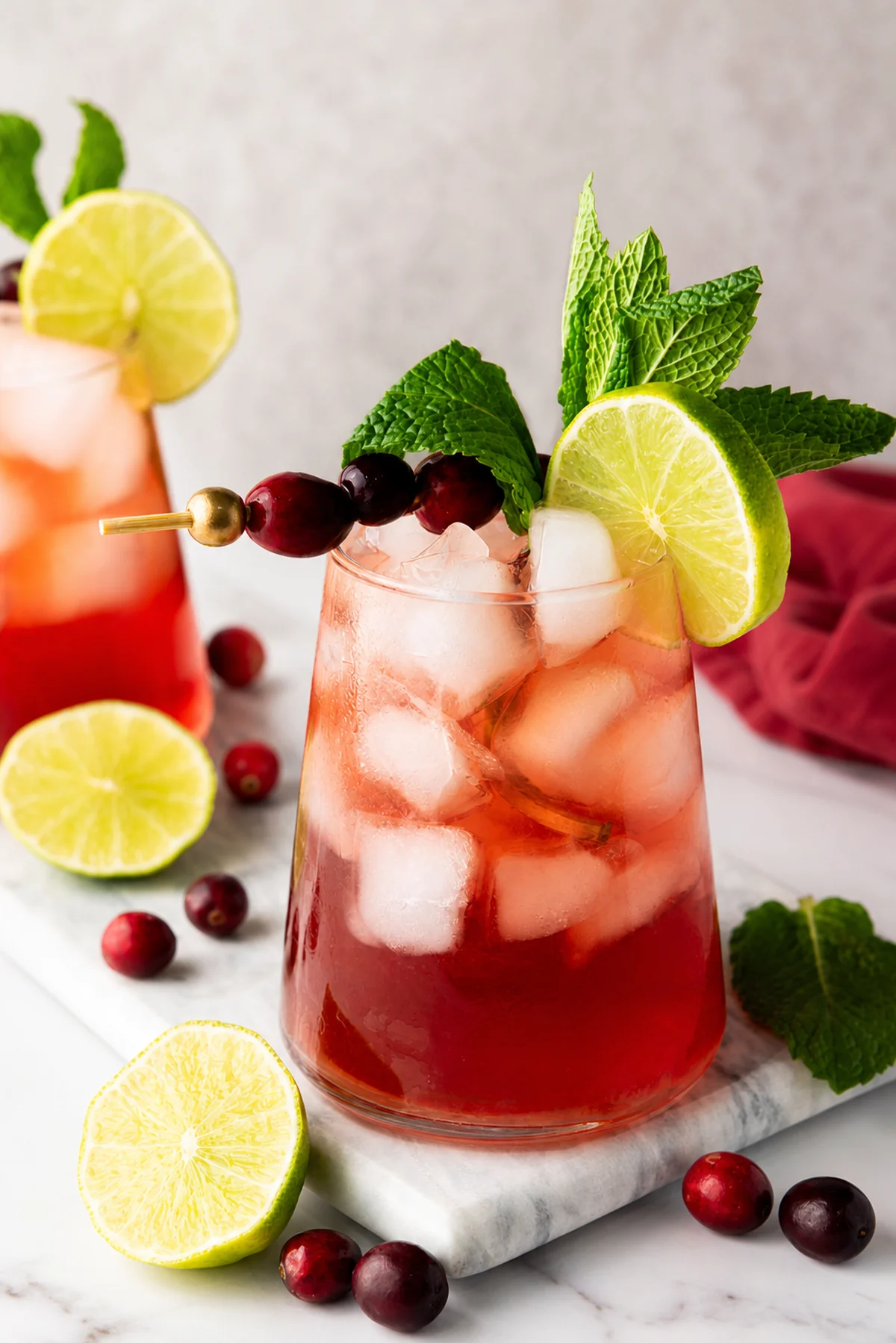 Closeup of a cranberry lime mocktail garnished with cranberries, lime, and mint.