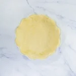 Homemade no-roll pie crust pressed into a white pie dish.