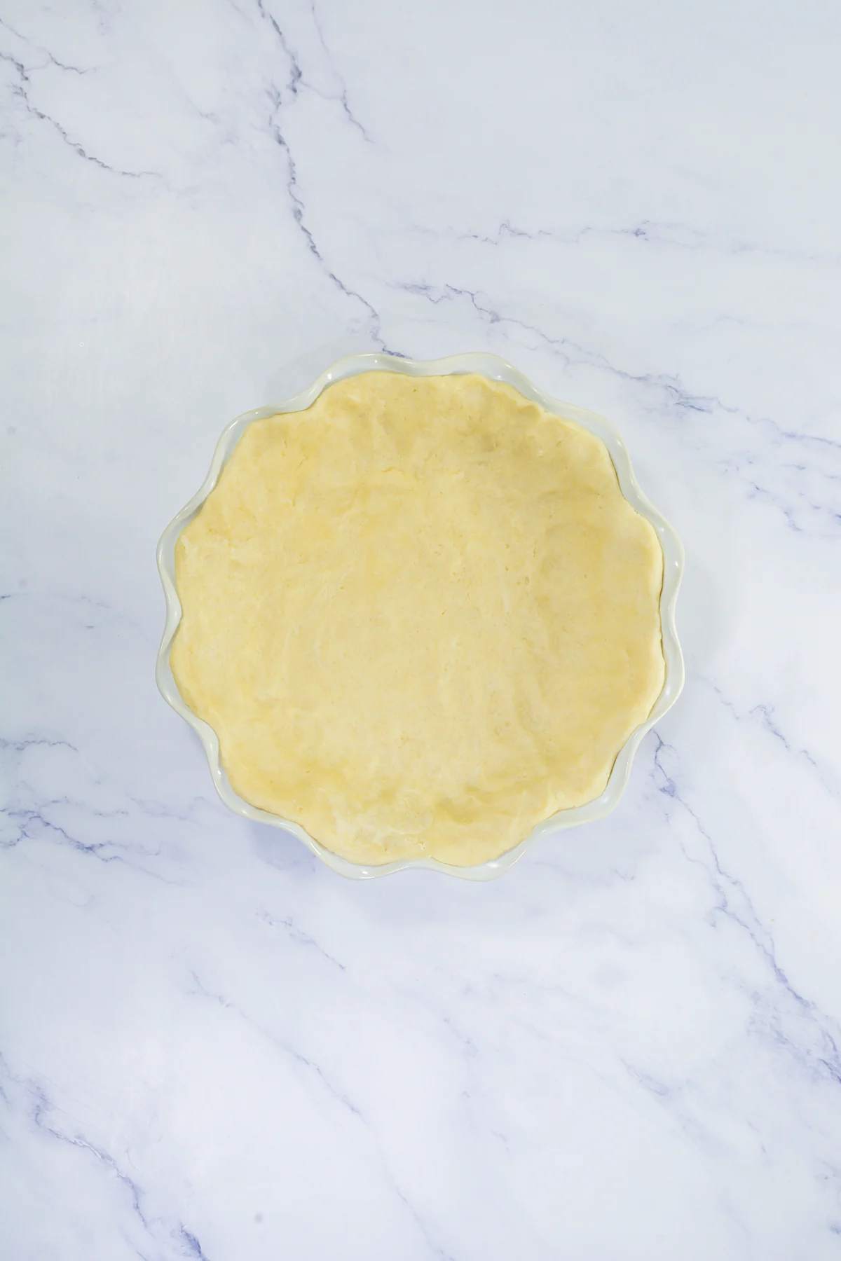 Homemade no-roll pie crust pressed into a white pie dish.