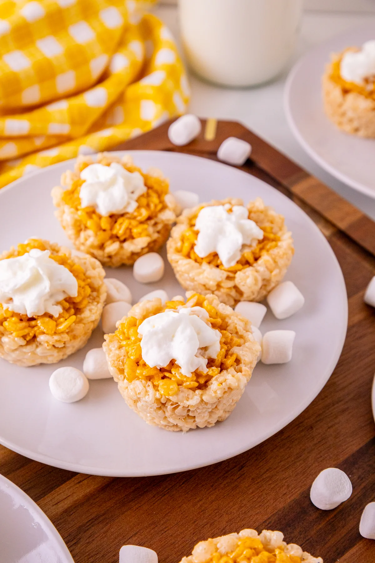 Mini Pumpkin Pie Rice Krispie Treats Grab-n-Go Thanksgiving Dessert Mini pumpkin pie Rice Krispie treats with whipped topping on a white plate.