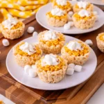 A tray of mini pumpkin pie Rice Krispie treats topped with whipped cream.