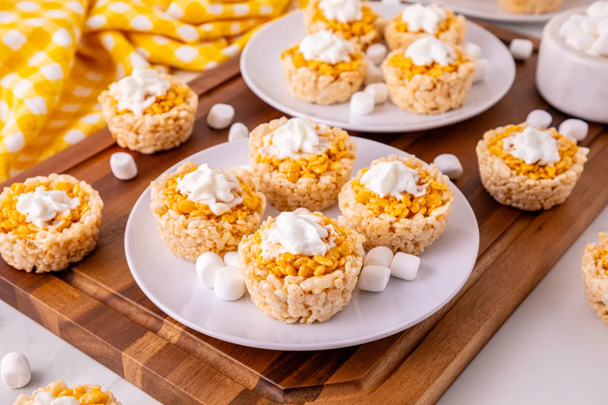 A tray of mini pumpkin pie Rice Krispie treats topped with whipped cream.
