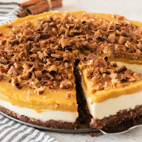 Whole layered no bake pumpkin cheesecake with one slice removed.