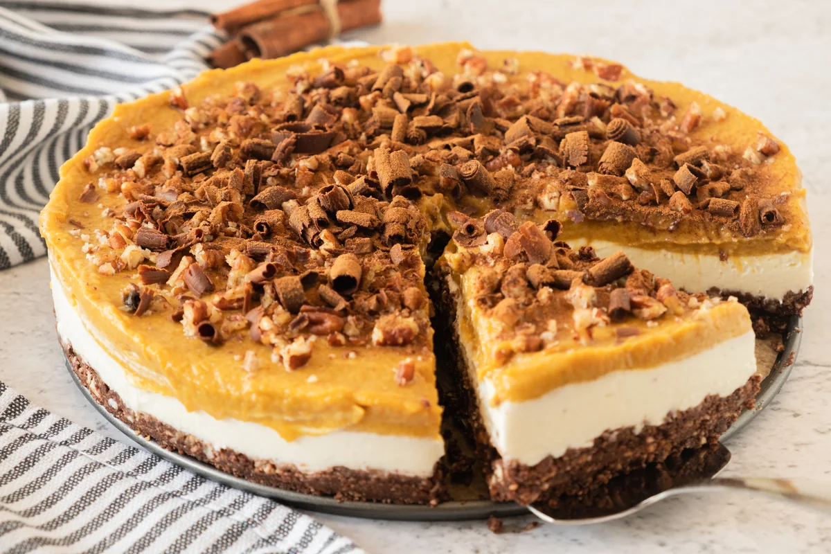 Whole layered no bake pumpkin cheesecake with one slice removed.
