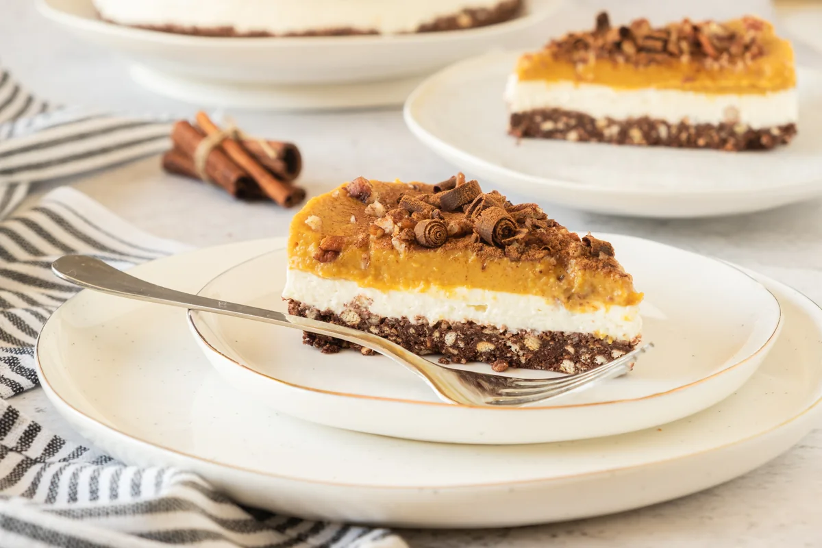 A slice of layered no bake pumpkin cheesecake on a white plate.