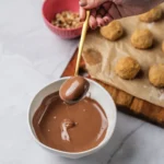 Peanut butter ball dipped in melted chocolate with shaped balls in the background.