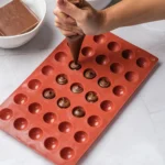 Nutella piped into small portions in a silicone mold before freezing.