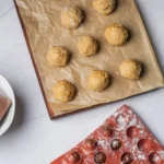 Peanut butter balls shaped on parchment paper before chocolate dipping.