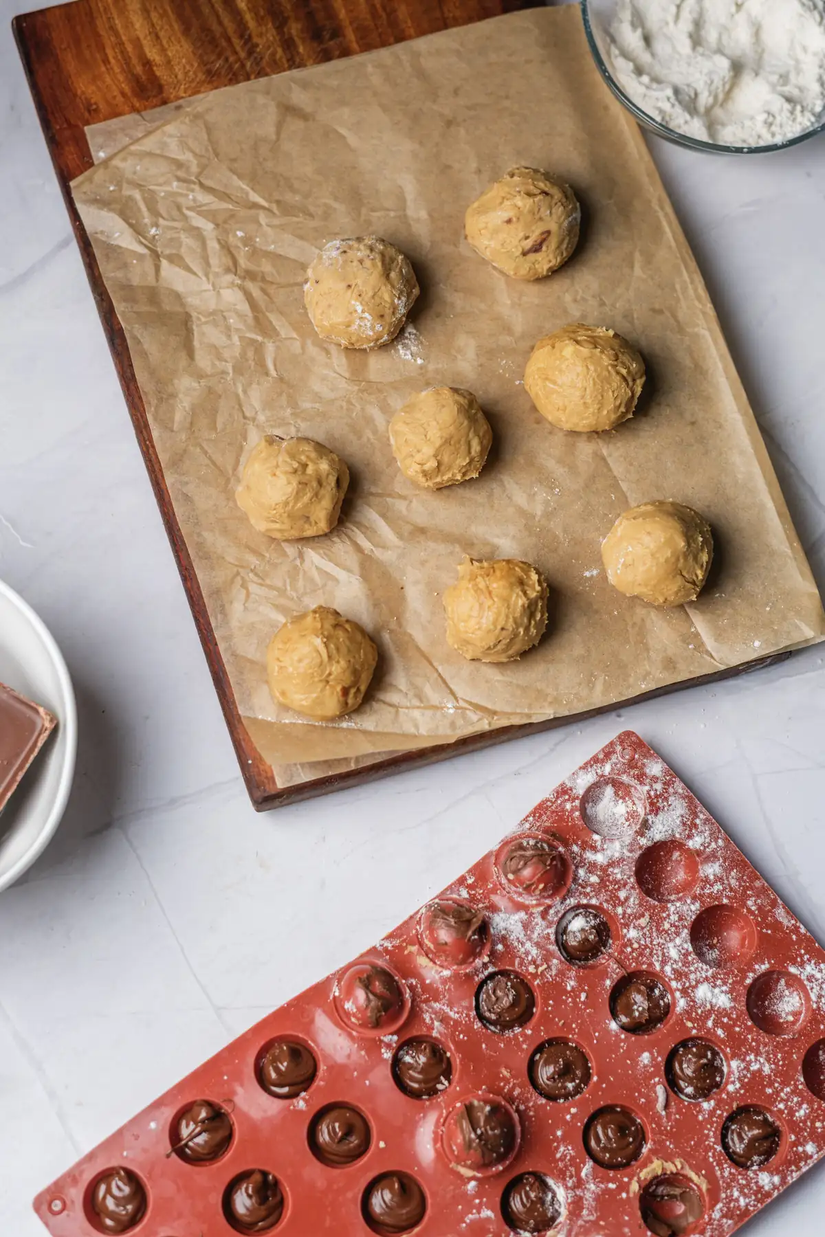 Peanut butter balls shaped on parchment paper before chocolate dipping.