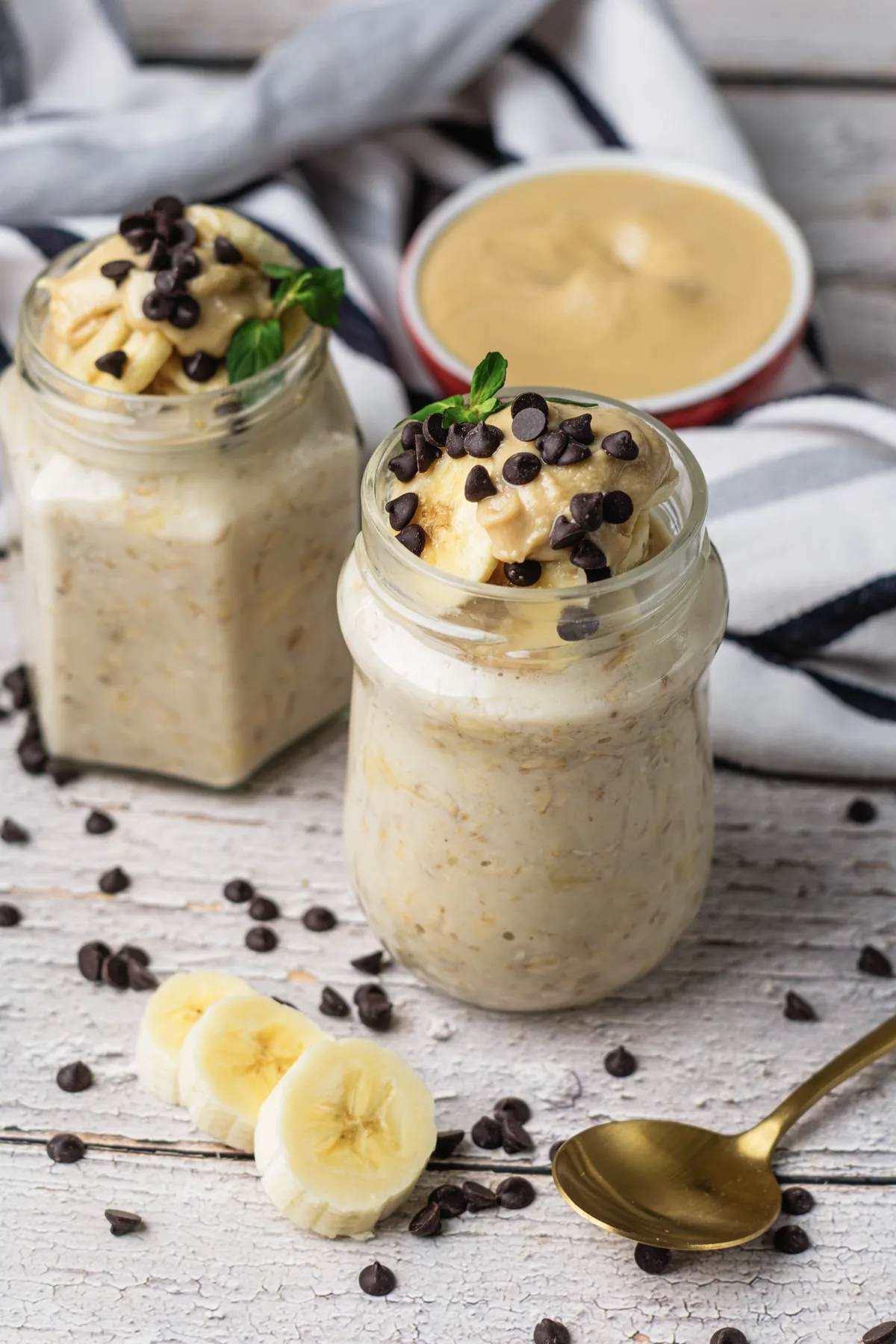 Peanut Butter Banana Overnight Oats Without Yogurt Creamy peanut butter banana overnight oats in jars with banana slices, chocolate chips, and peanut butter.