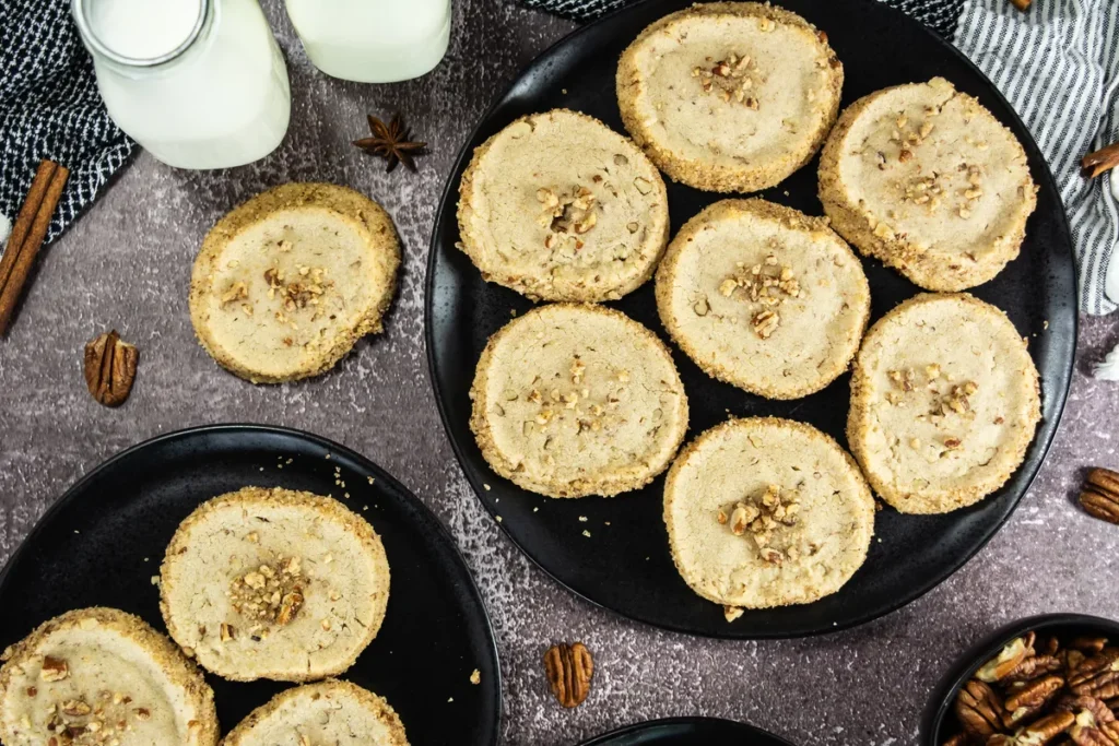 15+ Dessert Recipes for a Crowd Pecan shortbread cookies arranged on black plates with milk bottles and pecans.